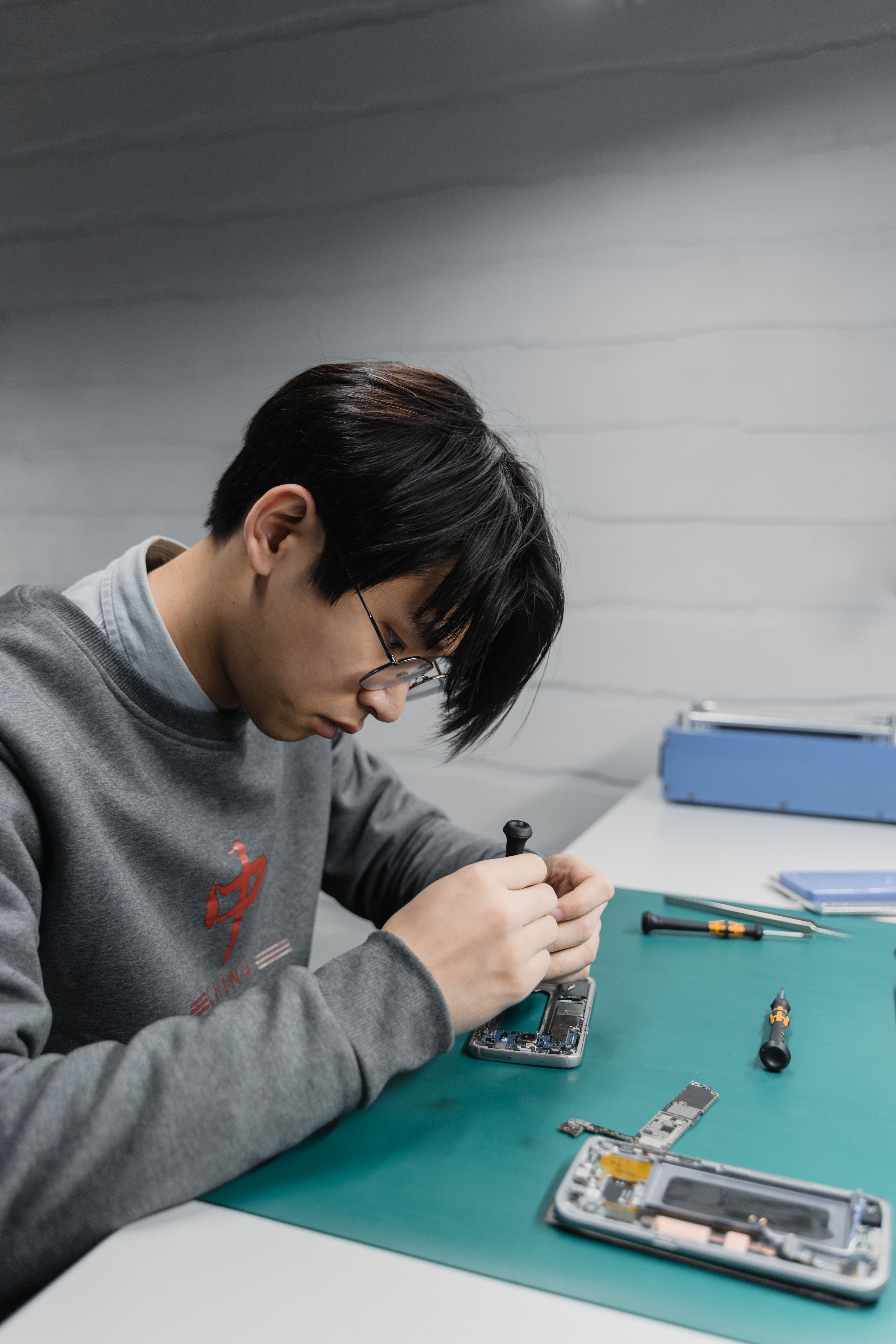 Technician repairing a smartphone at a workstation